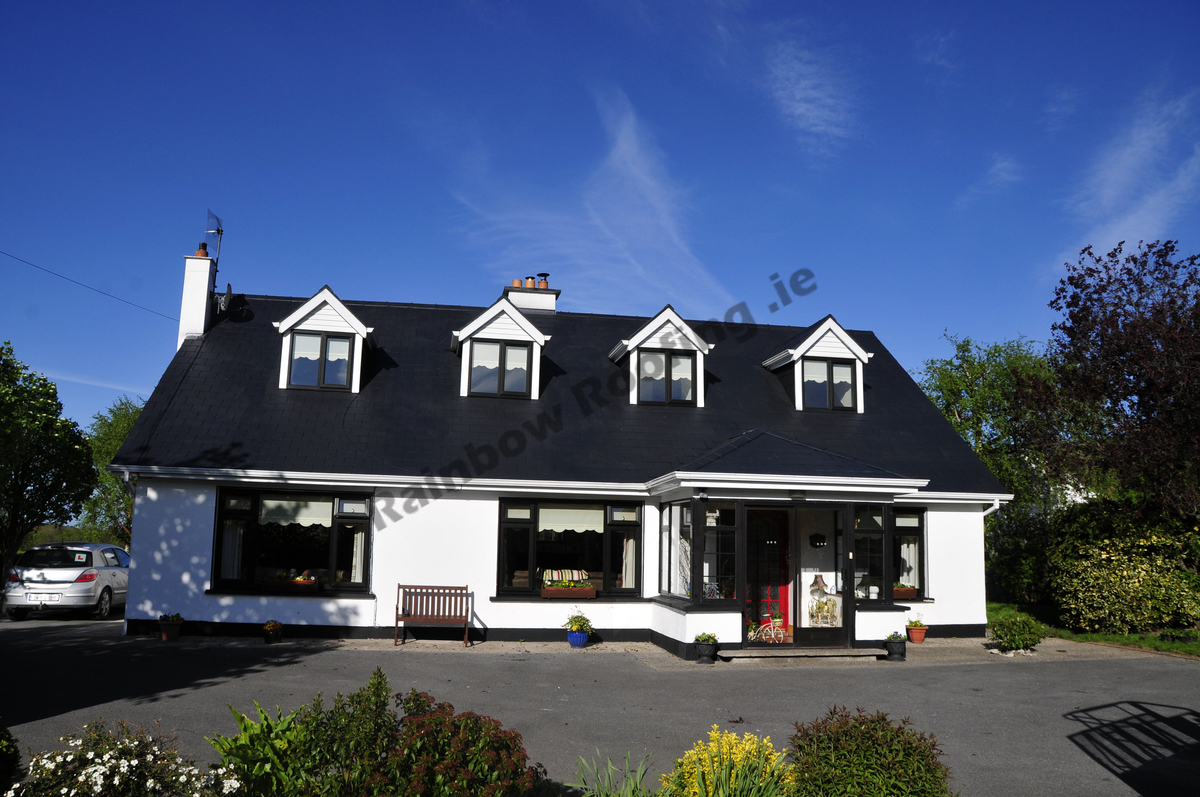 White bungalow house with newly spray painted dark blue roof tiles.
