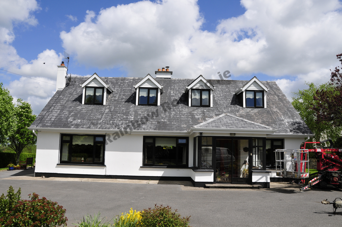 White Bungalow house with faded and discoloured roof tiles.